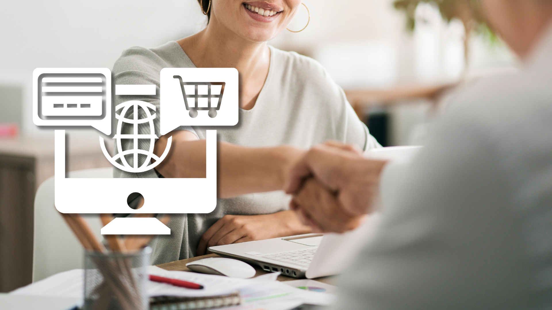 Handshake at a desk with a laptop, with a white online shop icon beside it – hiring an in-house e-commerce specialist