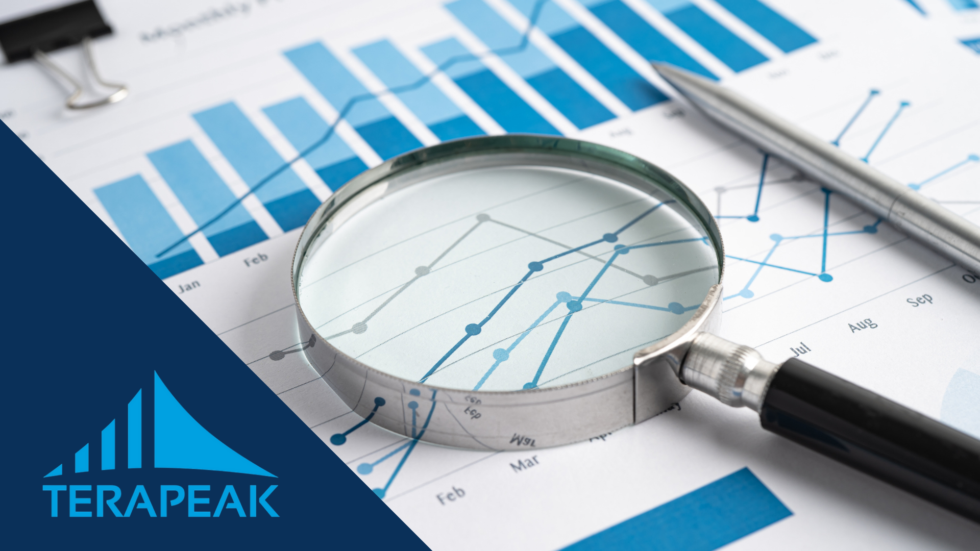 Magnifying glass and pen on printed sales charts with the logo of Terapeak, a tool for researching demand on eBay